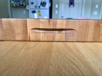 A closeup of the finger grooves of a wooden cutting board