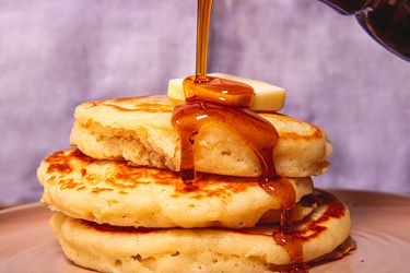 Side view of pouring syrup on pancakes