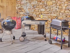 Three charcoal grills on an outdoor patio.