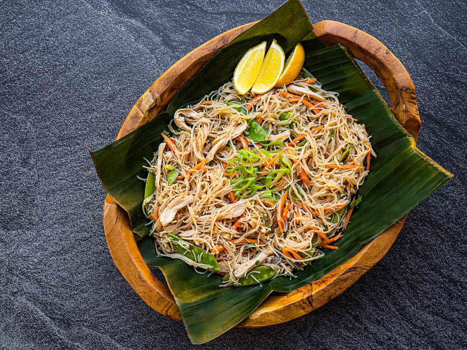 Pancit bihon served in a banana leaf-lined wooden bowl
