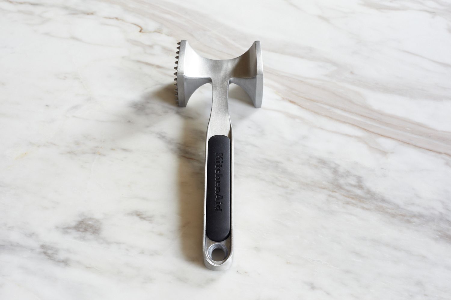 A mallet-style meat pounder on a marble surface