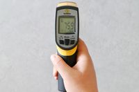 A person holding an infrared thermometer.