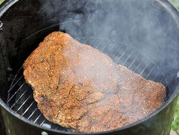 Seasoned brisket cooking in a smoker 