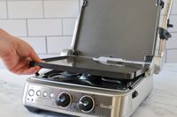 A person adding a plate to the Breville panini press.