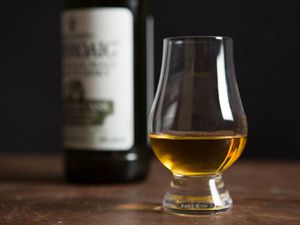 A glass of Islay Scotch whisky, with a bottle in the background.