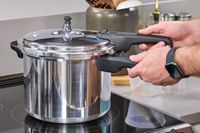 A person removes the lid on the IMUSA 7 Quart Stovetop Aluminum Pressure Cooker