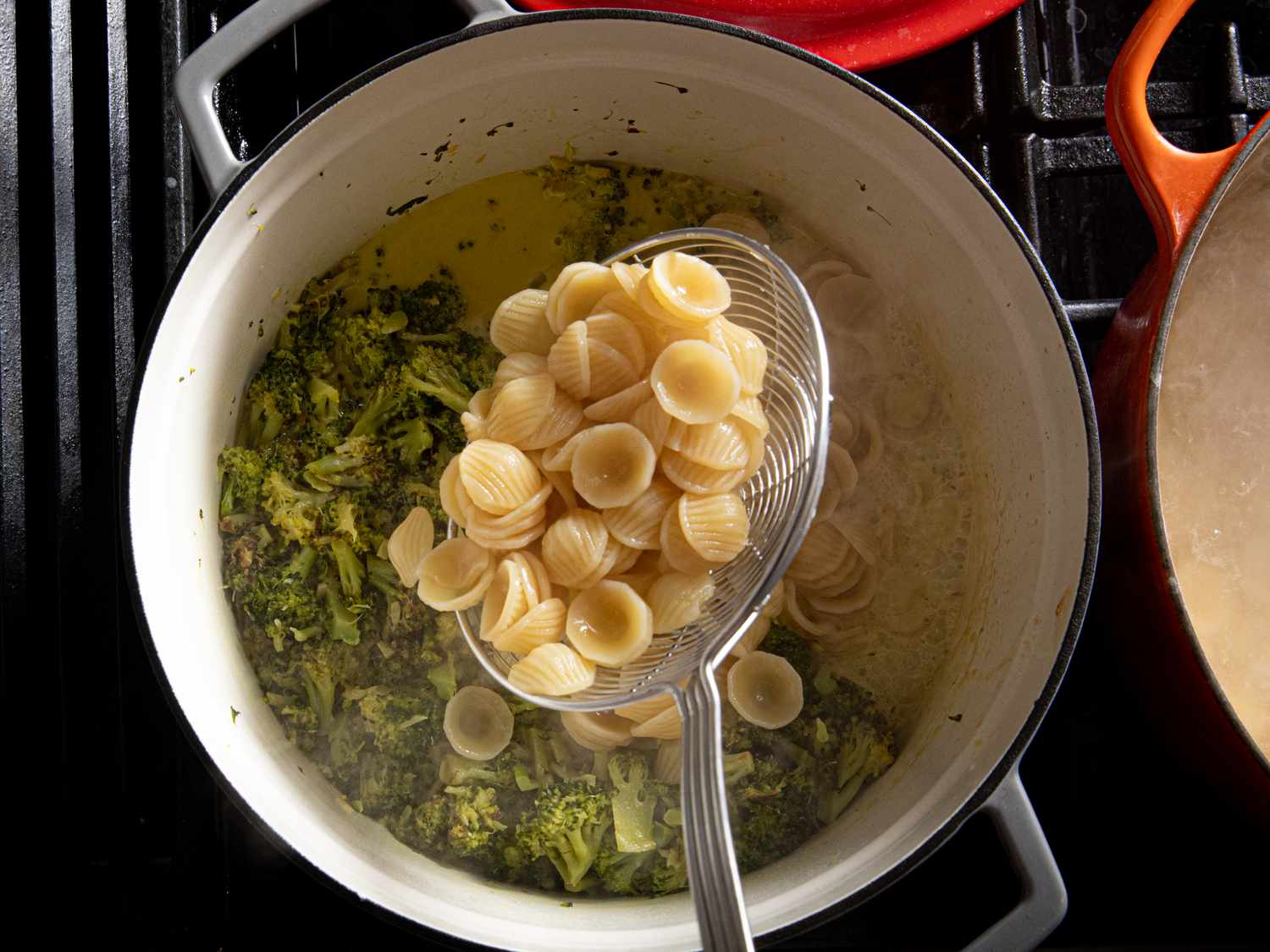 Orecchiette being added to broccoli sauce.