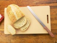 an overhead shot of the yoshihiro cutting board with a bread knife and sliced bread