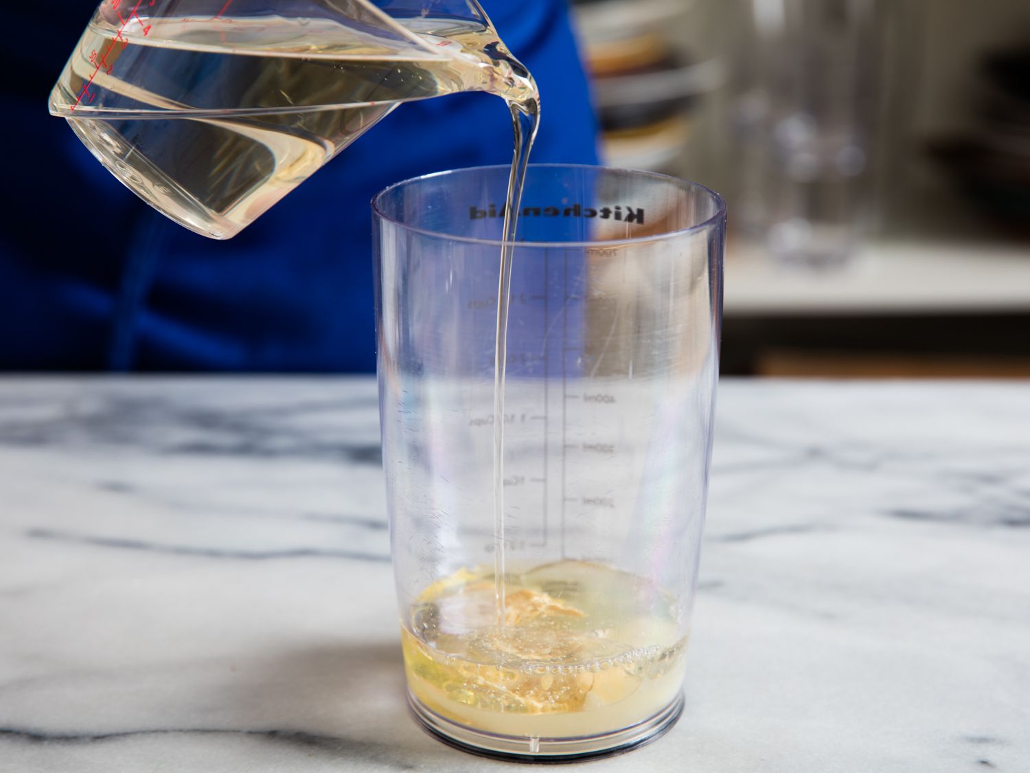 Pouring oil into a container for egg whites mayo. 
