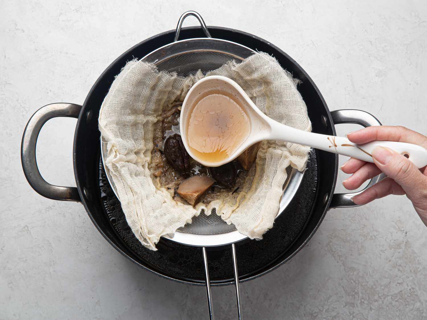 Overhead view of straining meat through cheesecloth