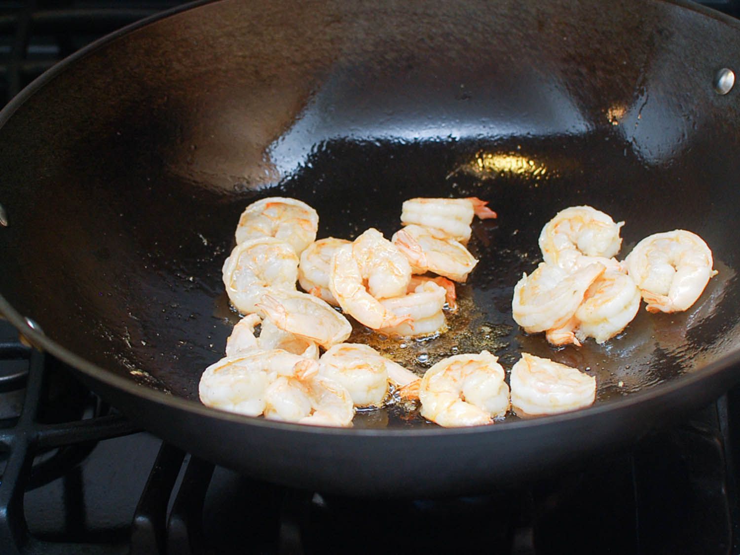 Shrimp are stir-fried in a wok.
