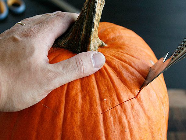 Cutting a lid off a pumpkin for carving, with a chef's knife