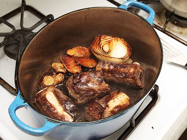 Short ribs and aromatics getting browned and charred in a Dutch oven.