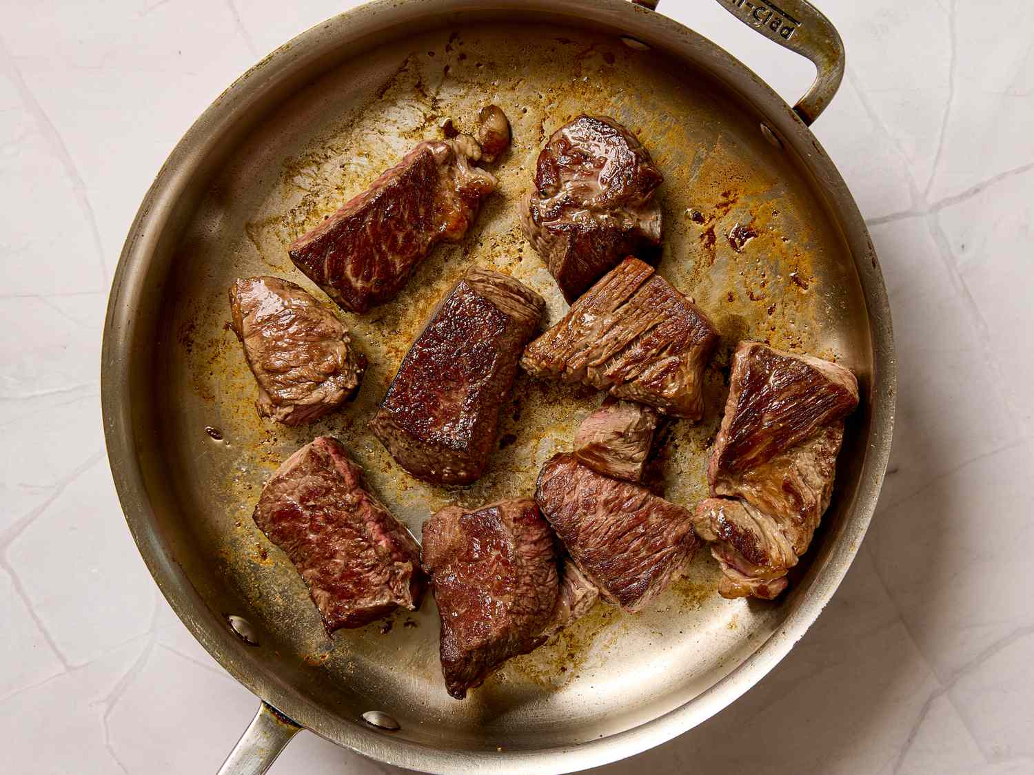 Chunks of browned beef cooking in a skillet