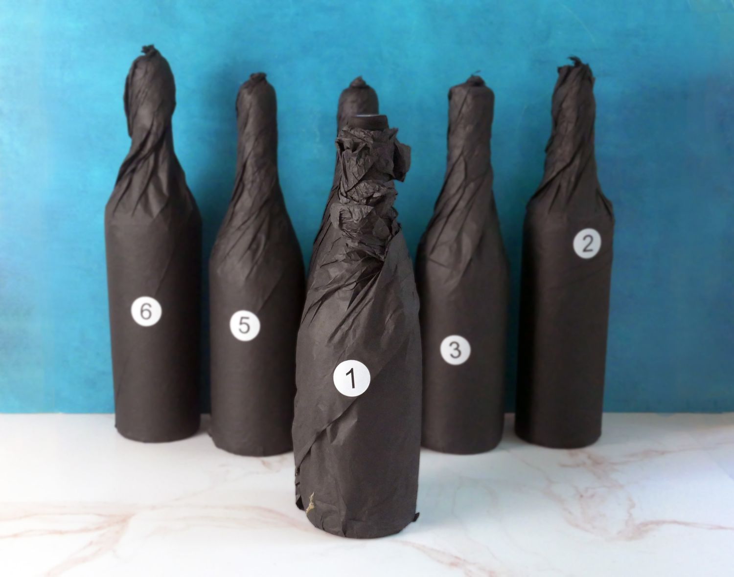 Wine bottles wrapped in black tissue paper with numbers on them