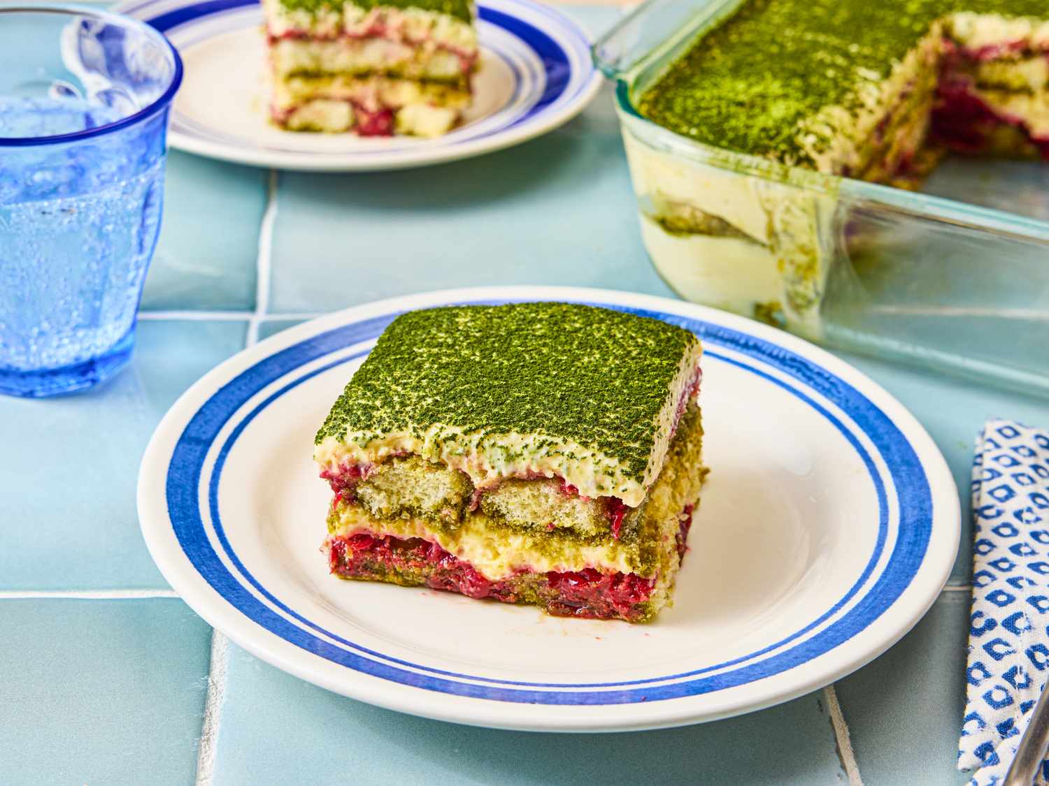 A plate with a slice of strawberry matcha tiramisu set on a table