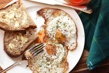 Two crisp fried eggs plated with slices of buttered toast