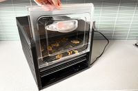 A person opening the front panel of the Samson Silent food dehydrator