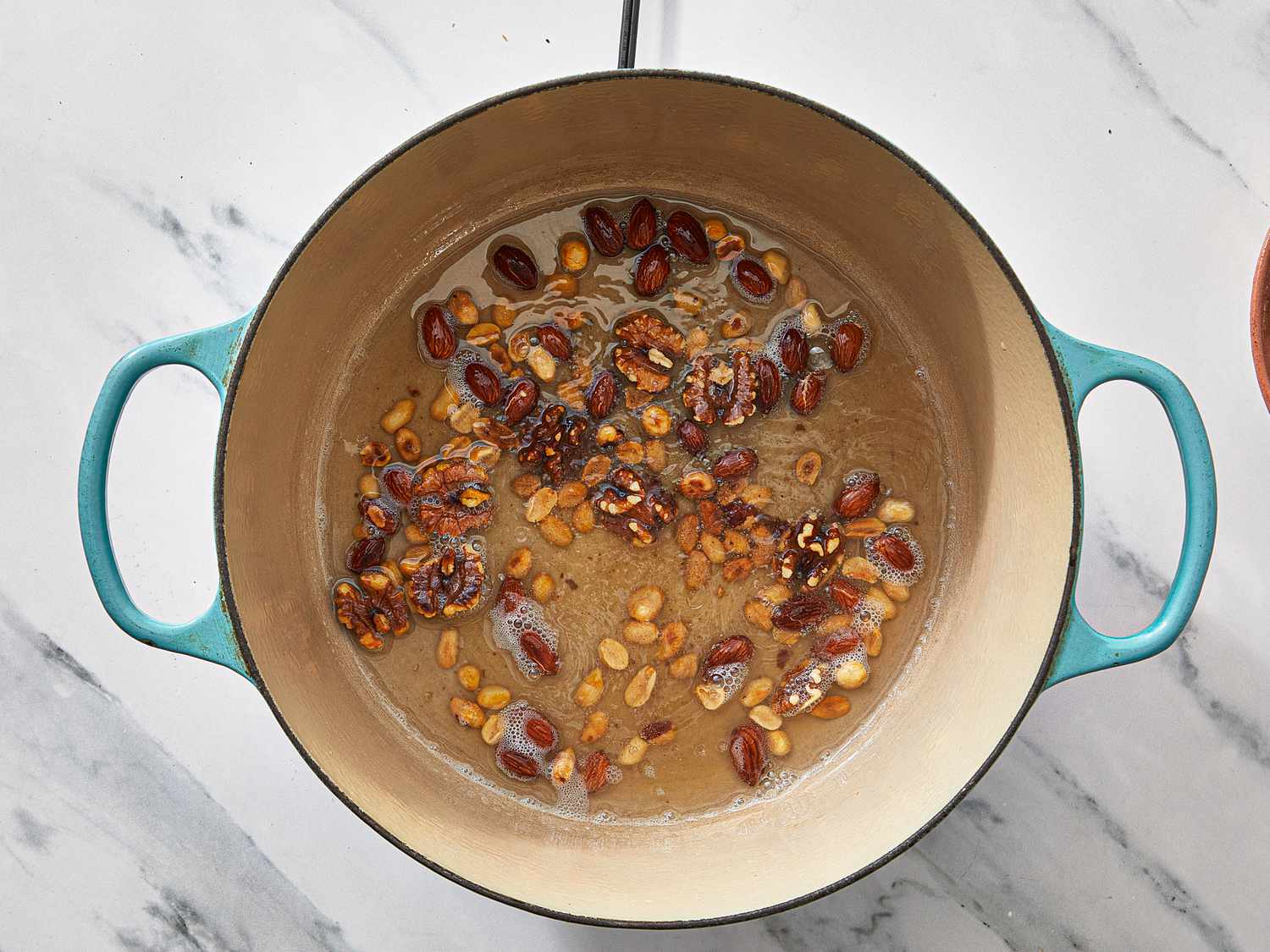 Ingredients roasting in a pot, including nuts and seeds, indicative of preparation steps for a recipe