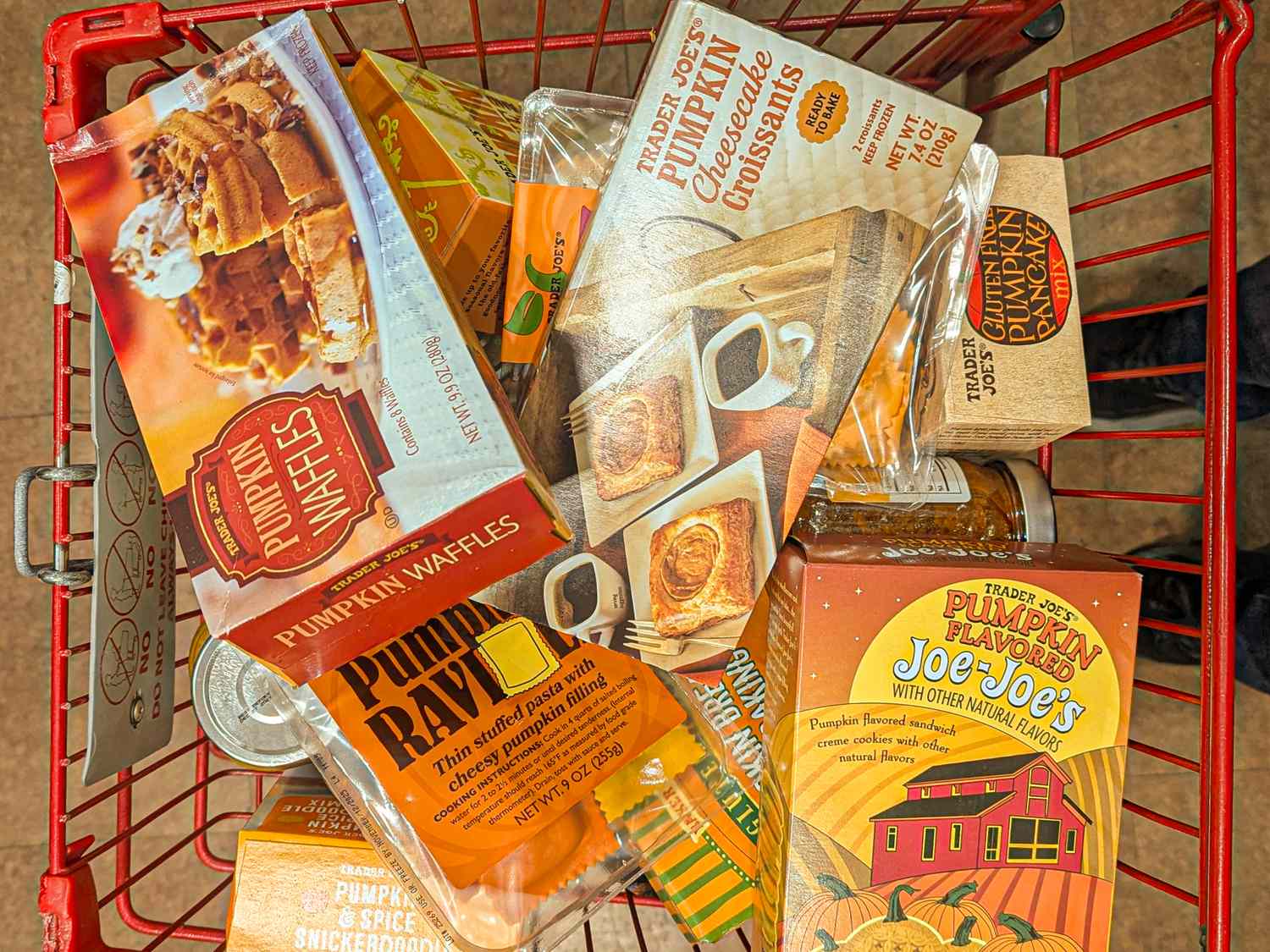 A shopping cart filled with Trader Joes pumpkinthemed products including waffles JoeJoes and pancake mix