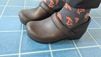 A person wearing the Dansko clogs with socks on.