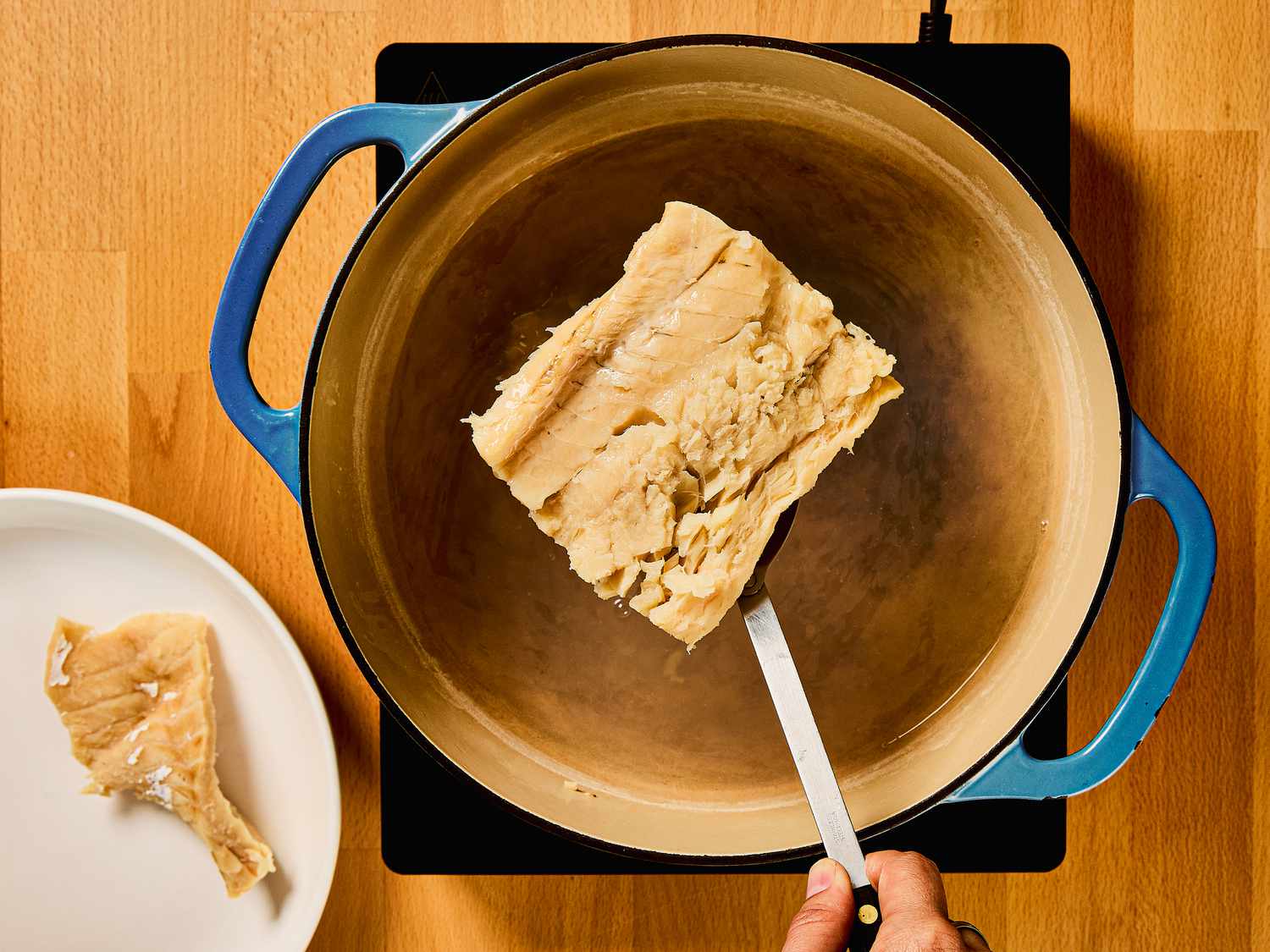 Removing cod from dutch oven and plating it onto a plate on the side 
