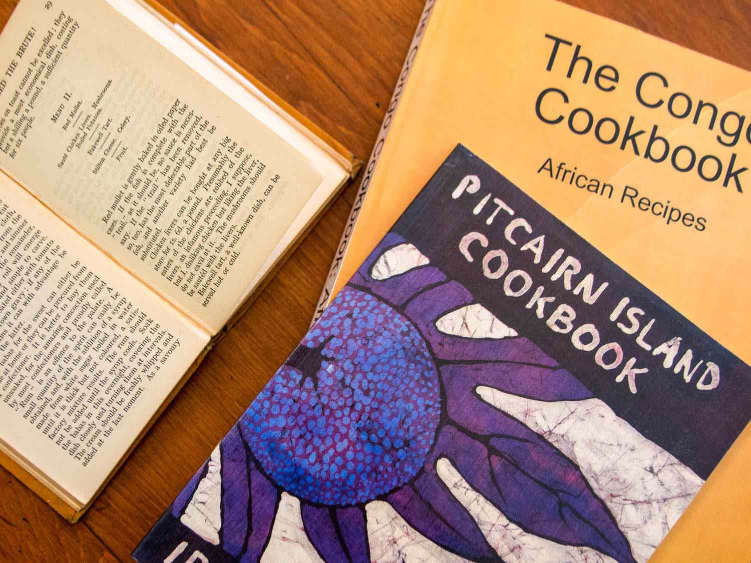 Sample favorite cookbooks from Sue Jimenez's collection: Feed the Brute!, The Pitcairn Island Cookbook, and The Congo Cookbook.
