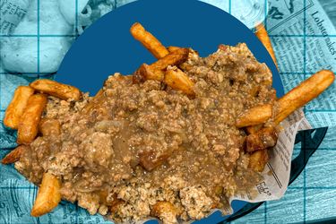 A plate of fries topped with minced meat and a sauce on a background resembling a blue grid and newspaper