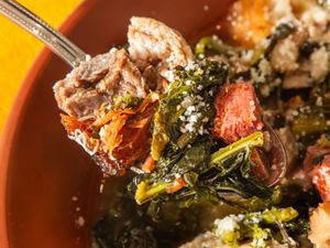 A spoonful of Italian wedding soup featuring meat greens and small pasta in a broth
