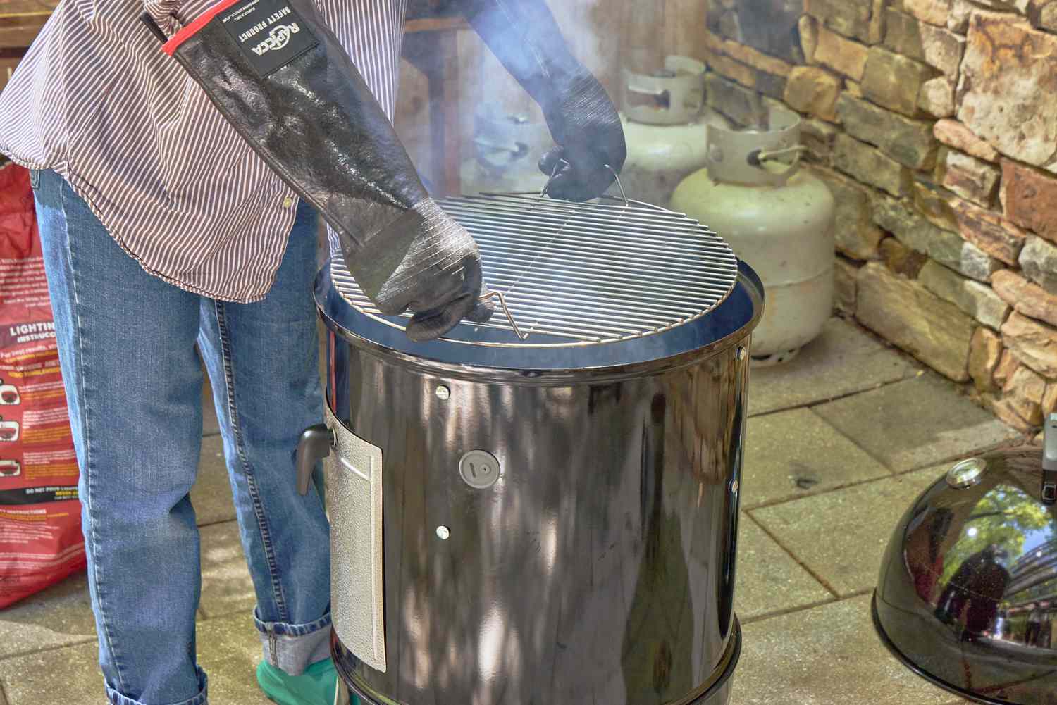 A person places the grate on the Weber 18-Inch Smokey Mountain Cooker