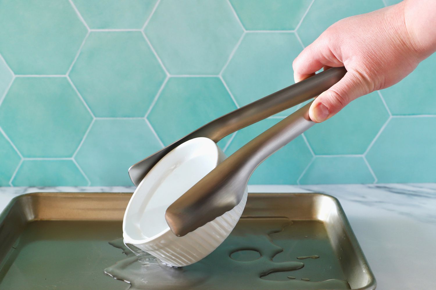 Hand using the Material Kitchen The Only Tongs to pick up a soufle dish