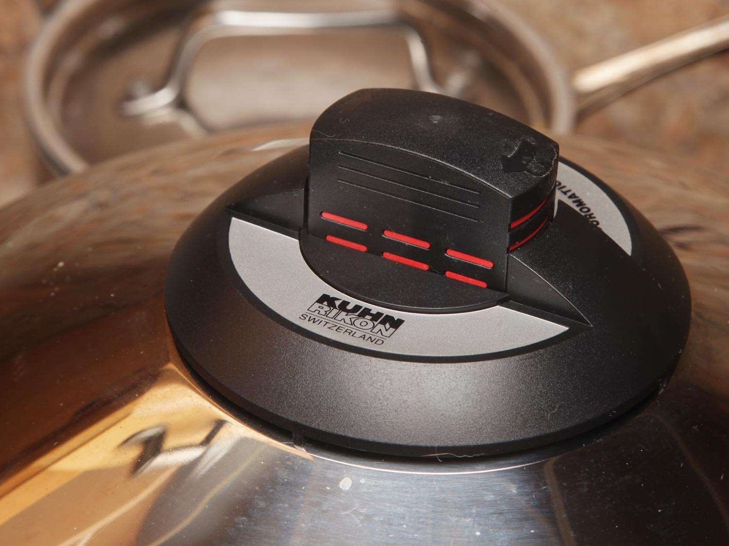 Close-up of the pressure indicator on a Kuhn Rikon stovetop pressure cooker. The lower red lines are visible, indicating that the pot is at full pressure.