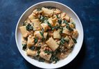 A bowl of paccheri pasta with flavorful sauce of beans and greens.