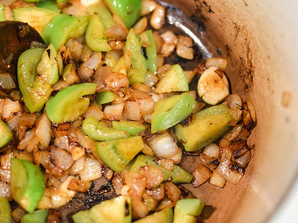 Onions, garlic, and tomatillos are cooked in the pan.