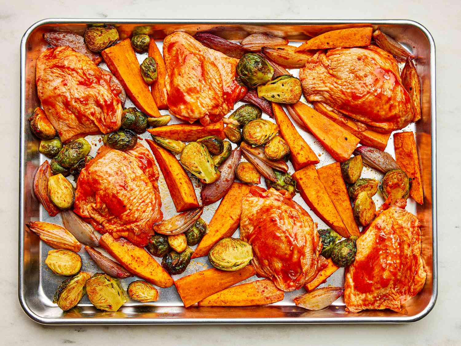 Marinated chicken added to sheepan of roasted vegetables 