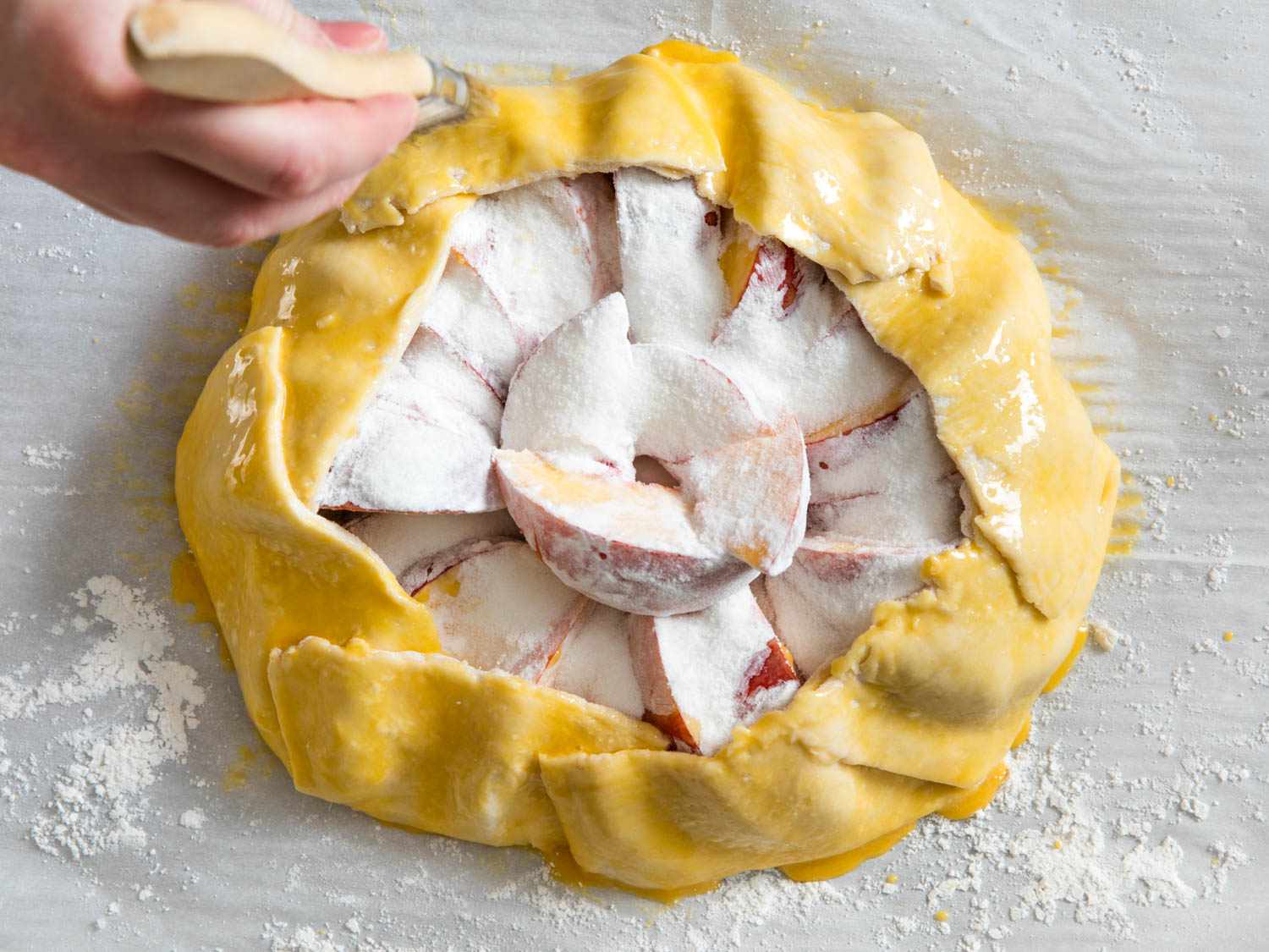 Overhead view of the galette rim being brushed with an egg wash.