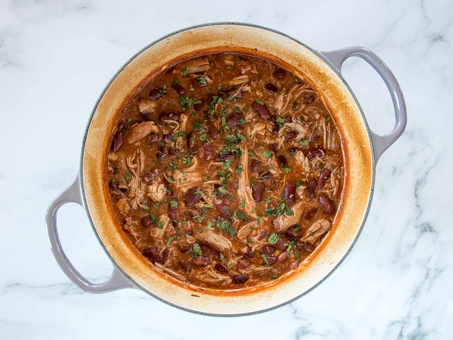 Pork and beans garnished with greens.
