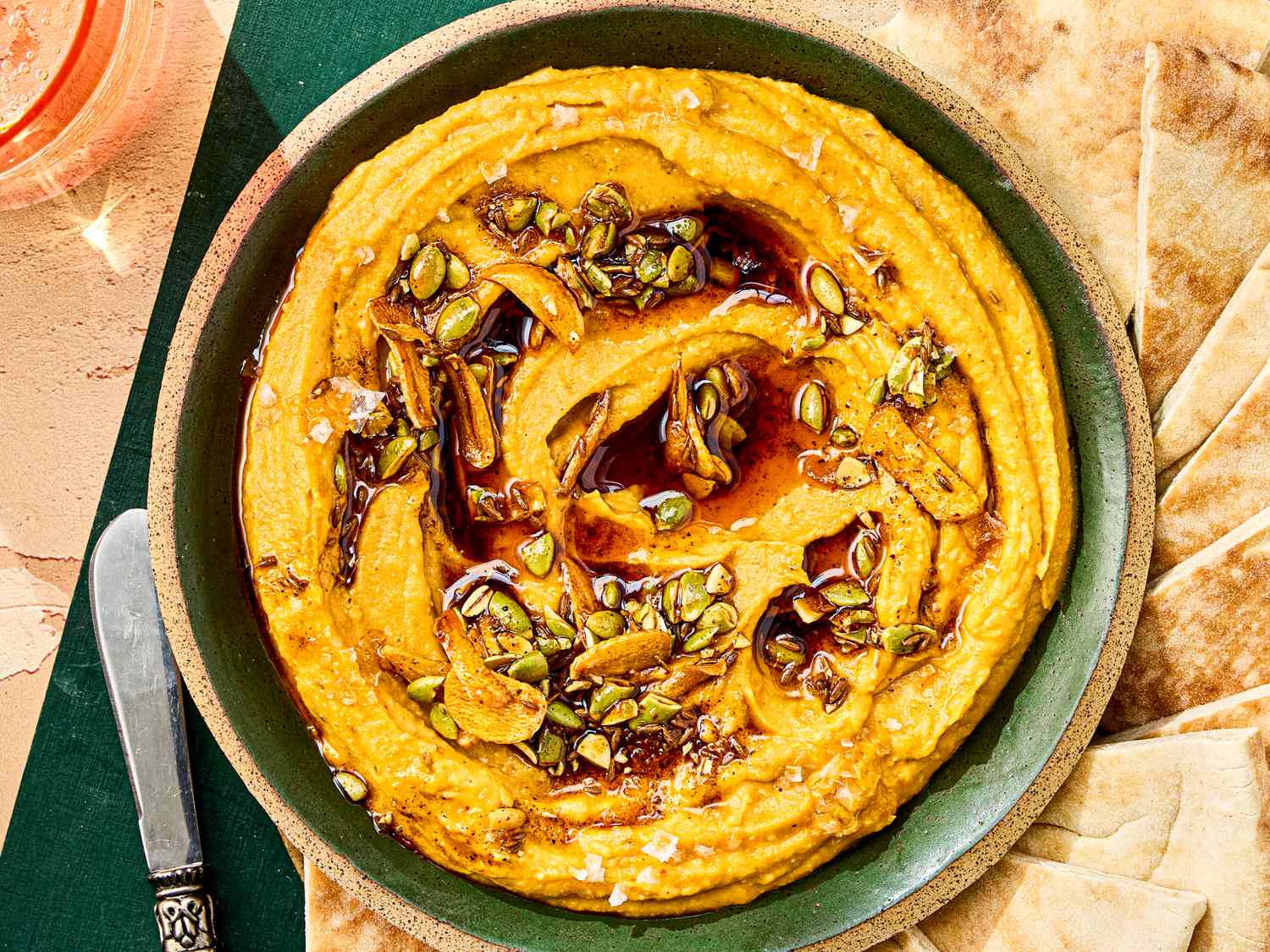 A bowl of sweet potato dip topped with seeds and served with flatbread pieces on the side