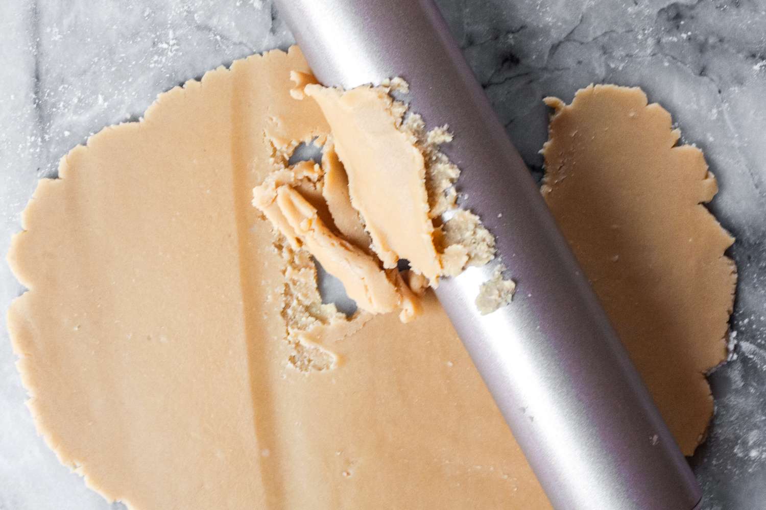 Rolling pin with dough on a marble surface dough sticking to the rolling pin during use