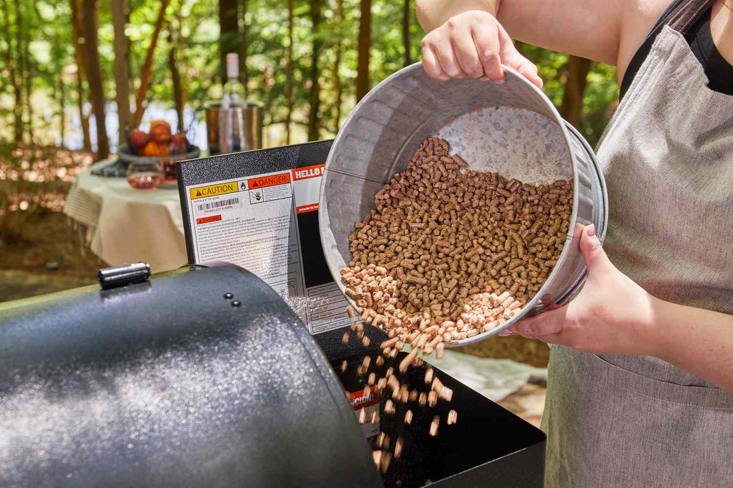 A person pouring wood pellets into the hopper of a Traeger grill