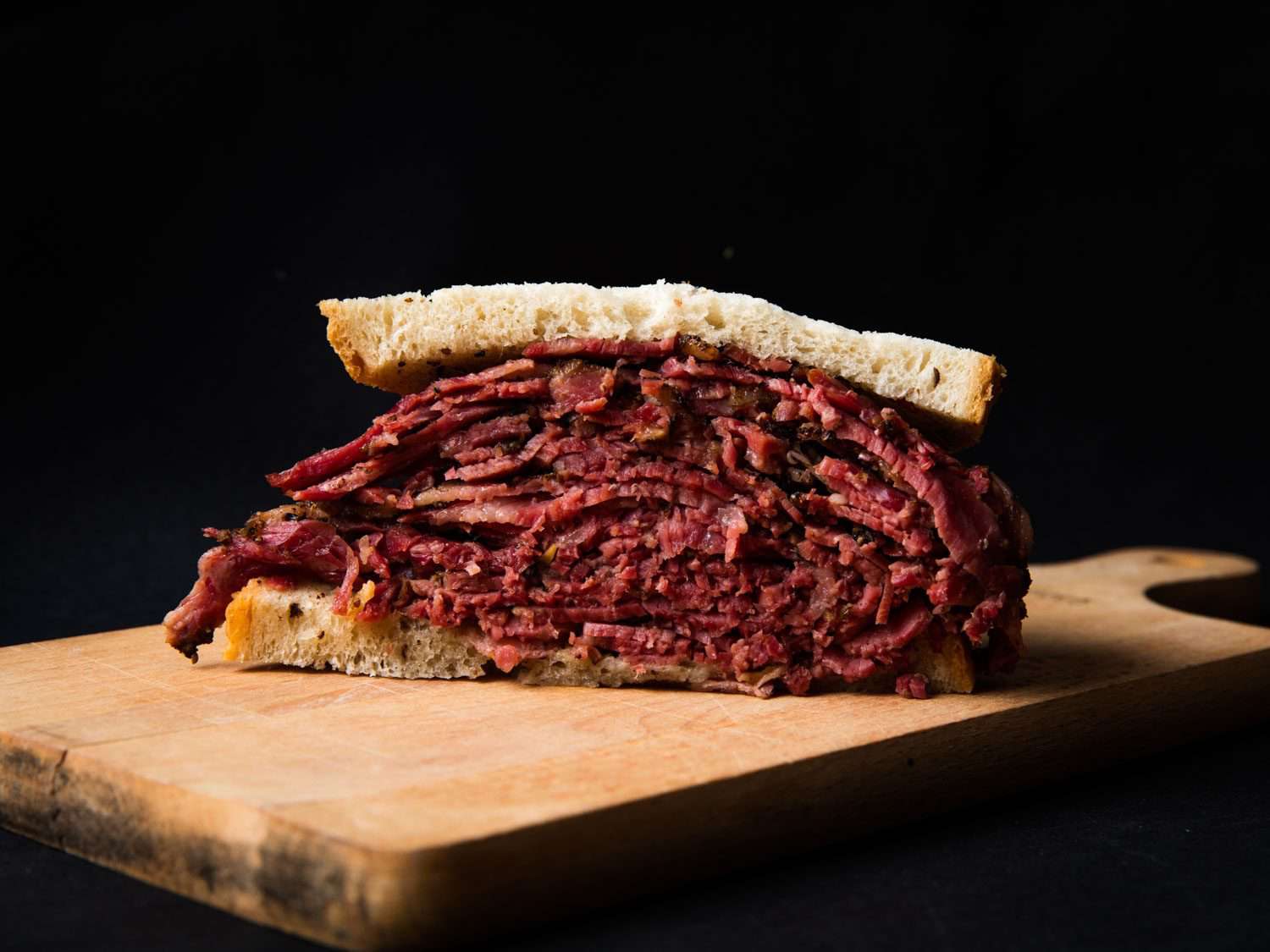 Profile view of a gigantic pastrami sandwich on rye bread.