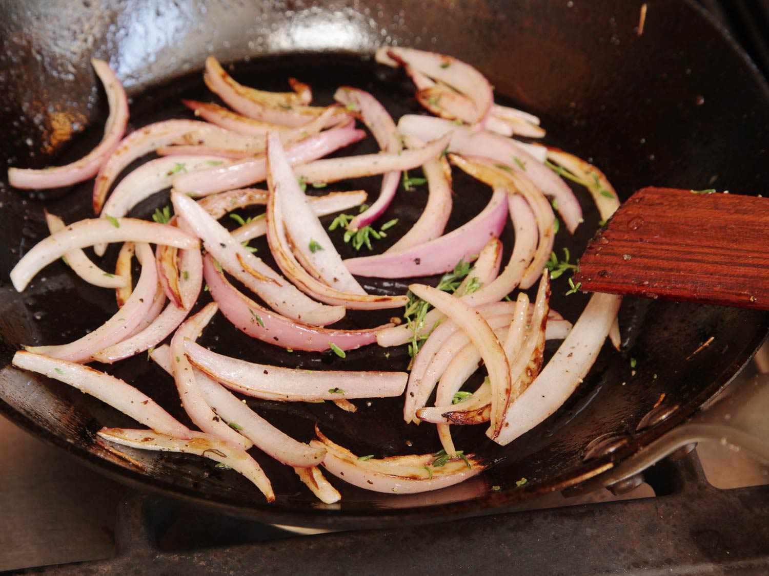 Large slivers of red onions browning in saute pan