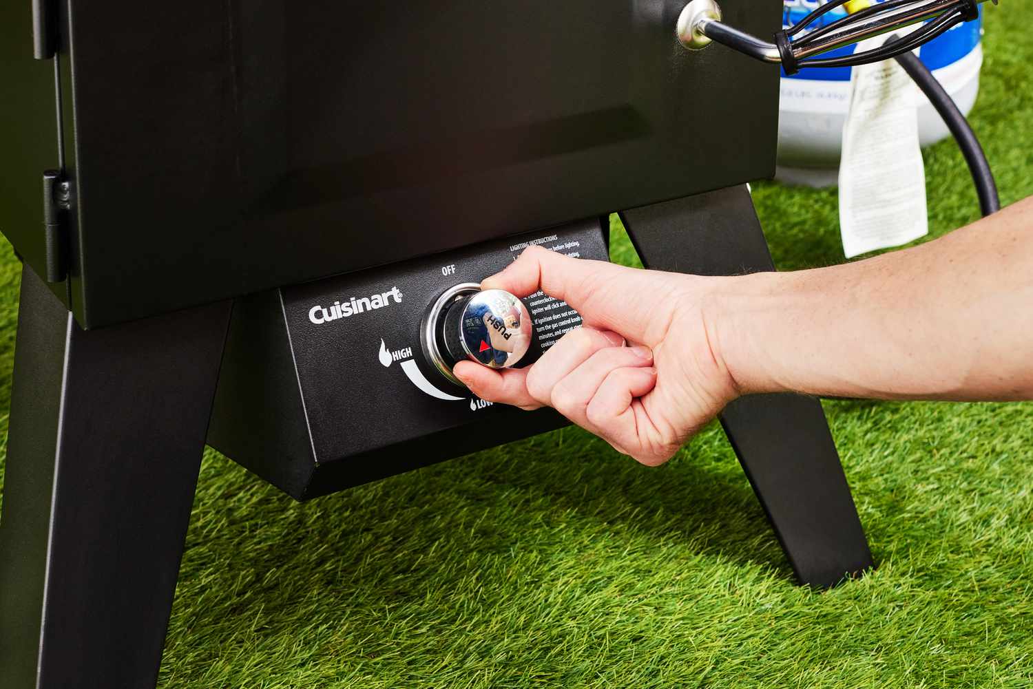 A person adjusting the temperature on the Cuisinart Vertical Propane Grill