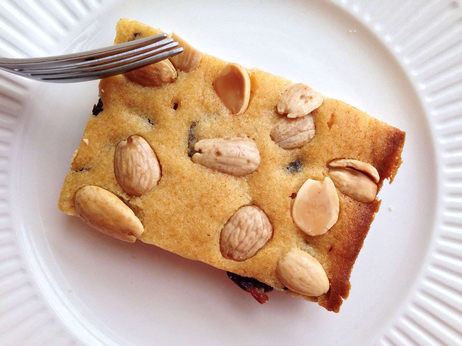 A square Marcona almond dried cherry blondie on a white plate.