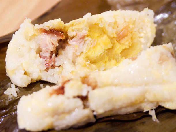 A cooked joong split open, showing mung bean softened into a paste and cured pork belly. 