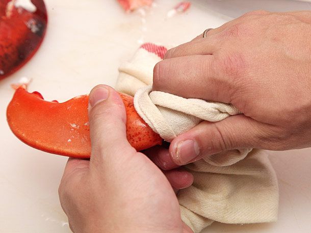 Holding a dish towel over a lobster claw to twist off the knuckle