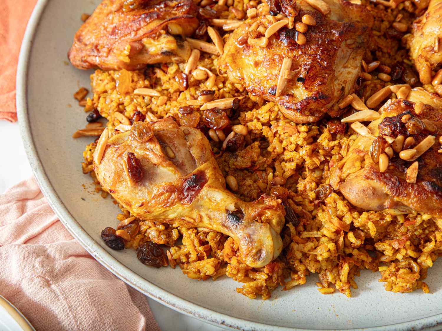 A dish of chicken served on spiced rice garnished with nuts and raisins
