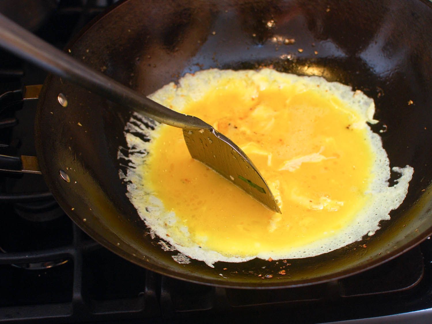 The beaten egg mixture is added to the wok.