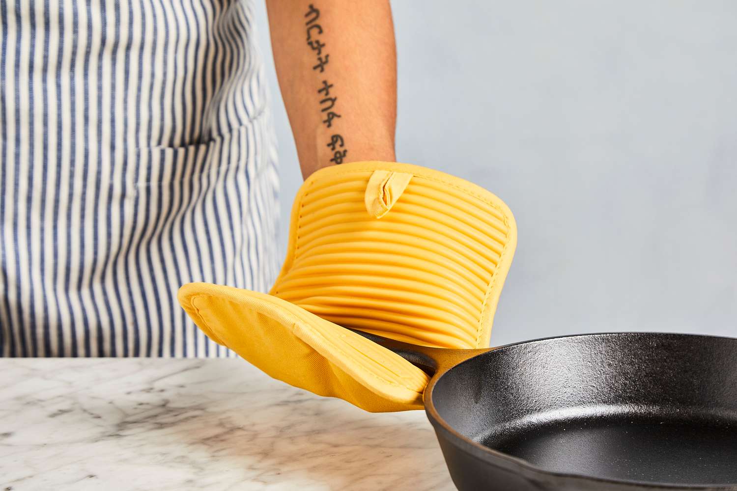 a person using the kitchenaid pot holder to hold the handle on a cast iron skillet