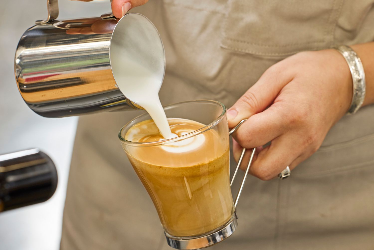 A person pouring milk into espresso made with the Lelit MaraX Espresso Machine PL62X-120
